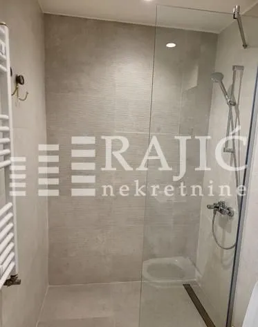 Modern bathroom with a walk-in shower and glass partition.