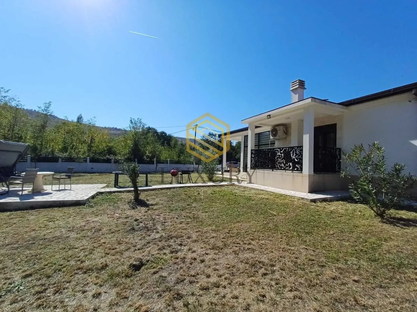 View of the yard and the exterior of the house with a paved patio.