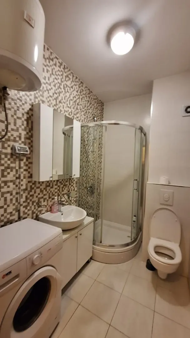 Bathroom equipped with a shower cabin, washbasin, toilet, and washing machine.