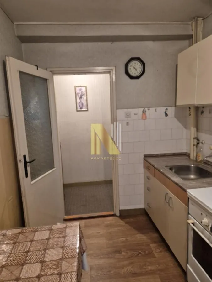Manja kuhinja sa sudoperom, elementima i šporetom.