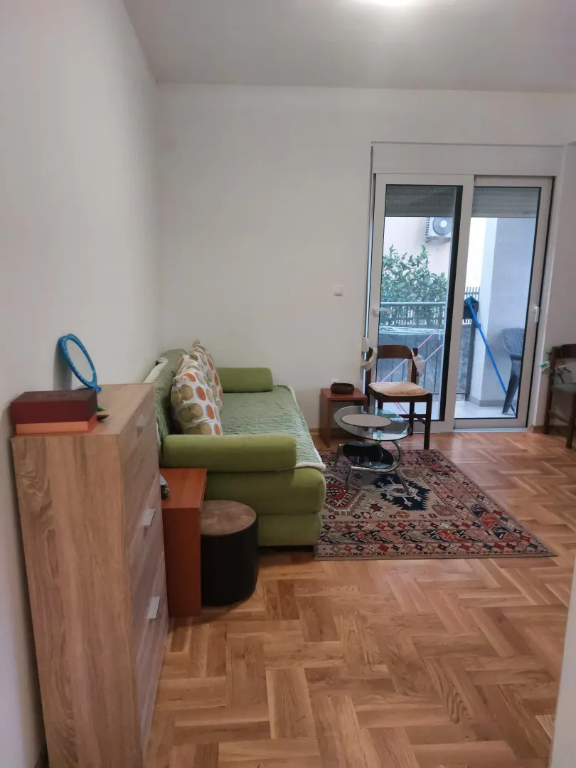 Living room with a green sofa, wooden furniture, and access to the terrace.