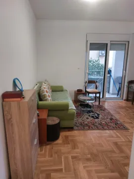 Living room with a green sofa, wooden furniture, and access to the terrace. - image 12