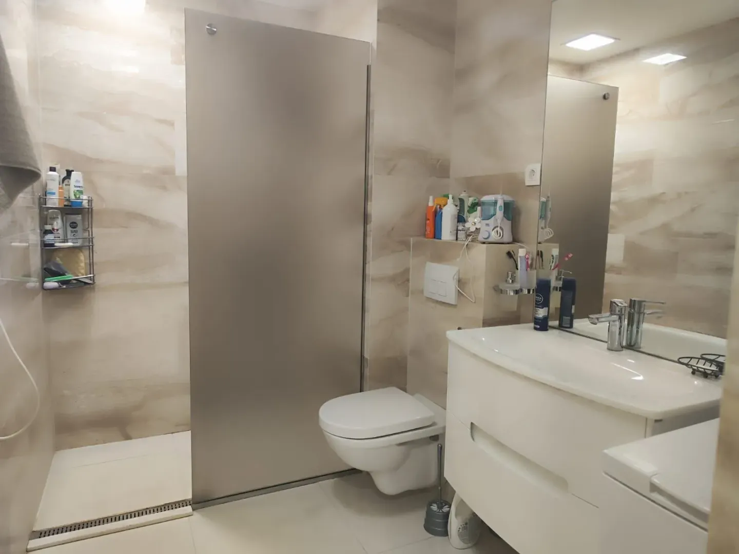 Bright bathroom with a shower cabin, toilet, and vanity sink.