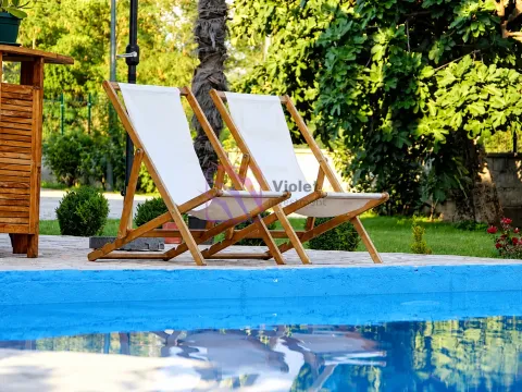 Sun loungers by the pool in a landscaped yard with greenery. - image 4