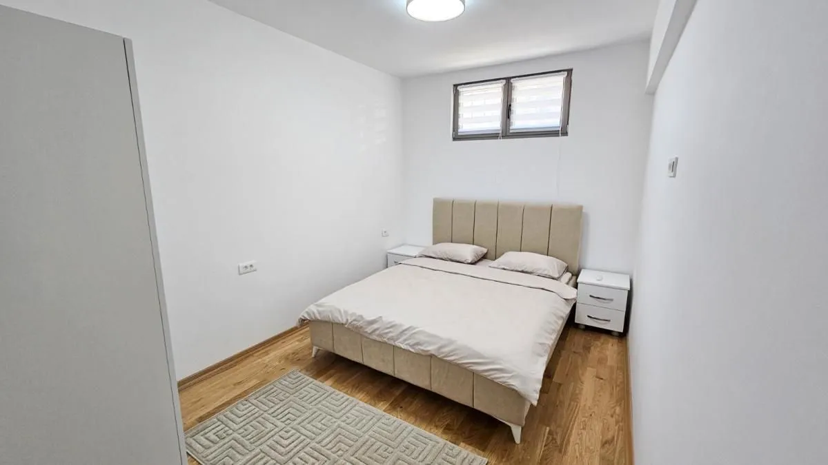 Namještena spavaća soba sa bračnim krevetom, noćnim stočićima i ormarom.