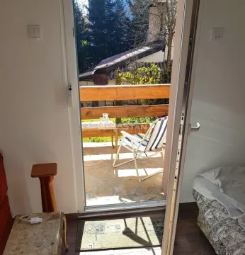 Pogled kroz balkonska vrata na terasu sa garniturom za sedenje. - image 13