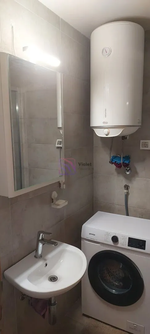 Kupatilo opremljeno umivaonikom, ogledalom, mašinom za veš i bojlerom.