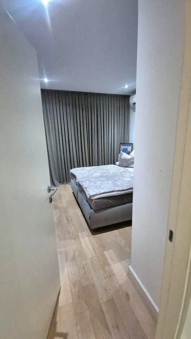Pogled iz hodnika na namještenu spavaću sobu sa bračnim krevetom.
