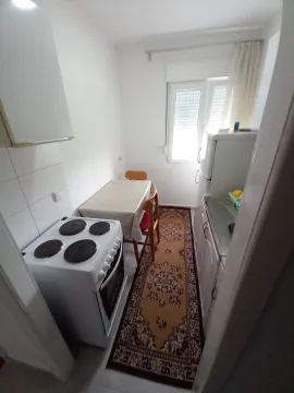 Small white kitchen with a stove and dining table. - image 3