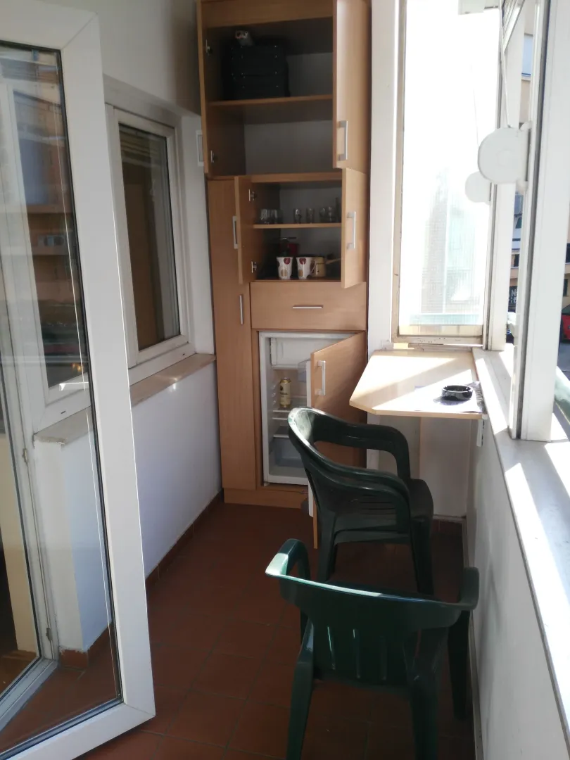 Enclosed balcony with built-in cabinetry and a small refrigerator.