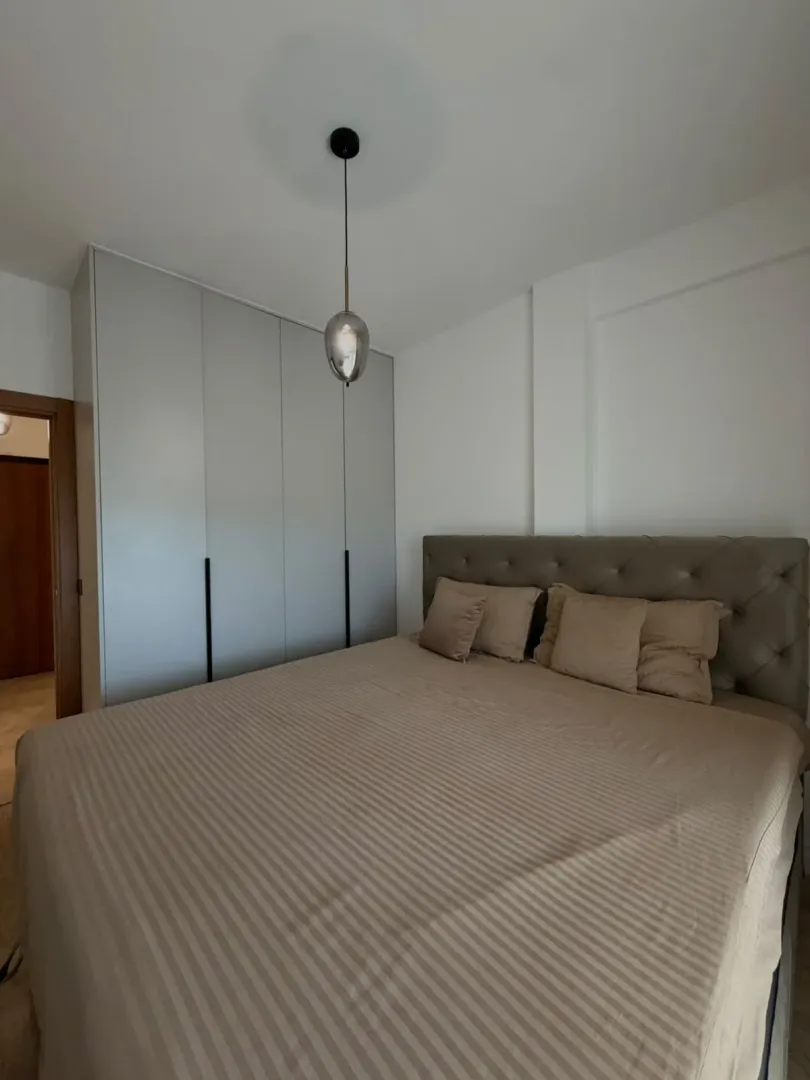 Furnished bedroom with a double bed and a fitted wardrobe.