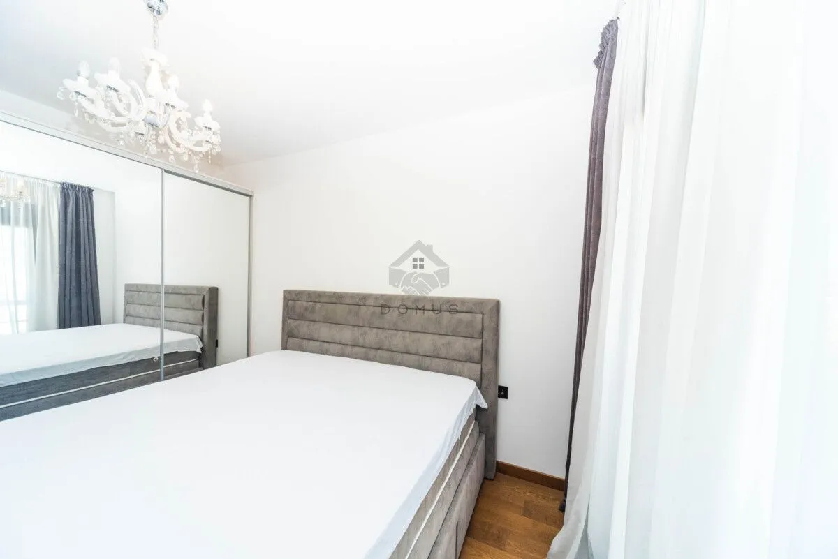 Spavaća soba sa bračnim krevetom, velikim garderoberom i lusterom.