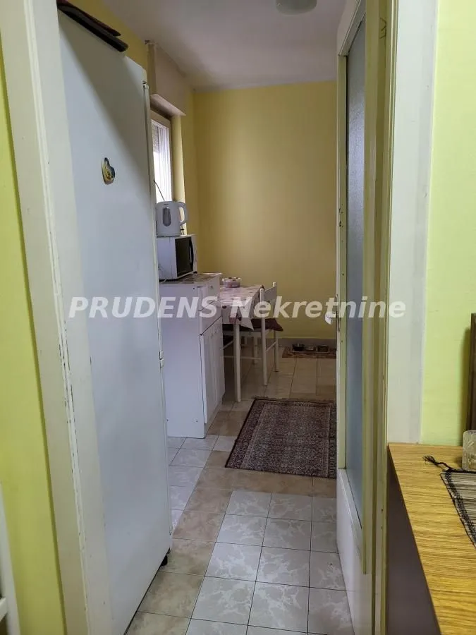 Manja kuhinja sa trpezarijskim stolom i frižiderom.