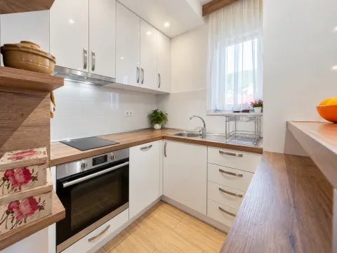 Small modern kitchen with white cabinets and a wooden countertop. - image 8
