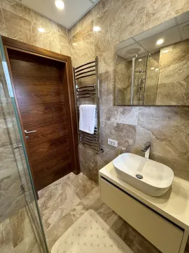 Modern bathroom clad in marble tiles with a washbasin and a walk-in shower. - image 8