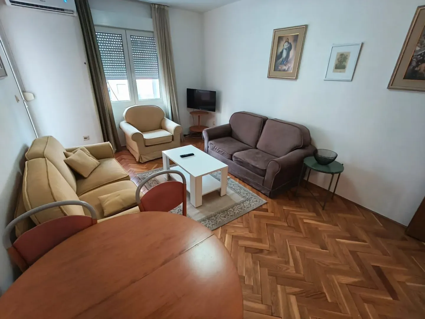 Dnevna soba sa garniturom, foteljom, stočićem i trpezarijskim stolom.