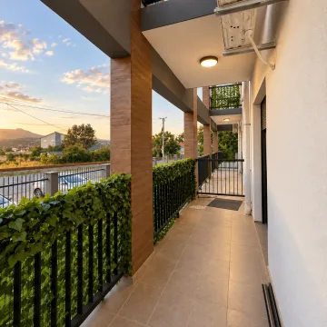 Dugački natkriveni balkon sa metalnom ogradom ukrašenom zelenilom i pogledom na okolinu. - image 7