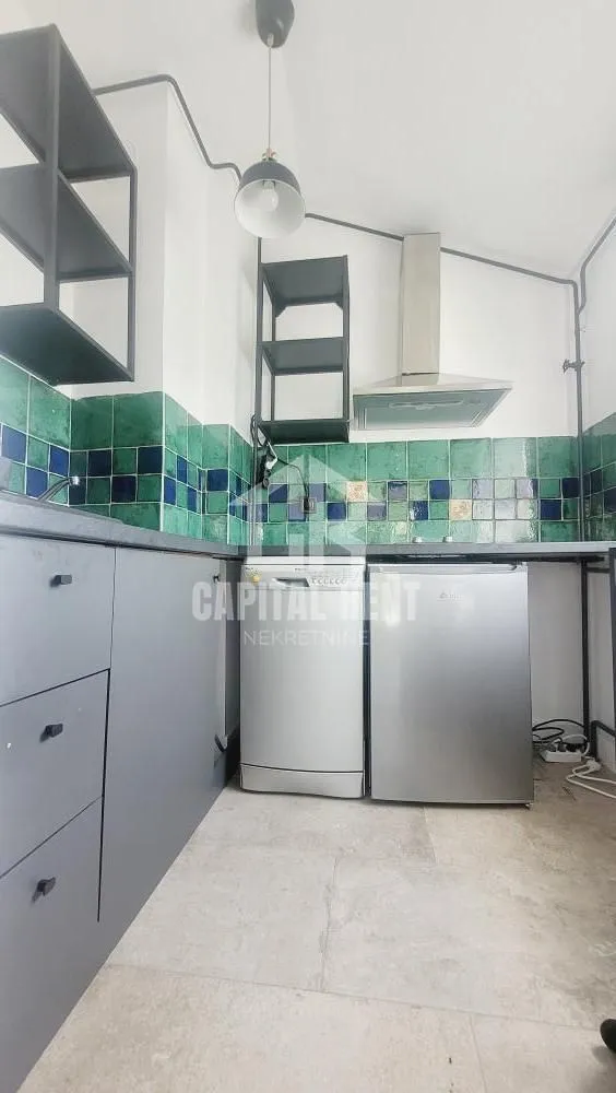 Small kitchen with grey cabinets and green ceramic tiles.