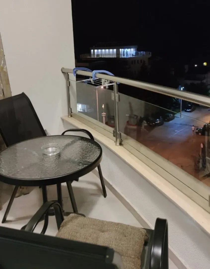 Small furnished balcony with a table, chairs, and a street view at night.