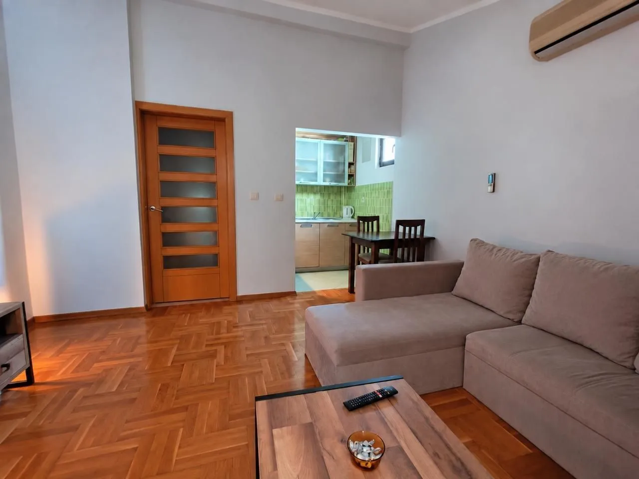 Living room with a sofa and a view of the kitchen in the background.