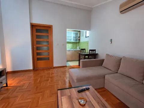 Living room with a sofa and a view of the kitchen in the background. - image 2