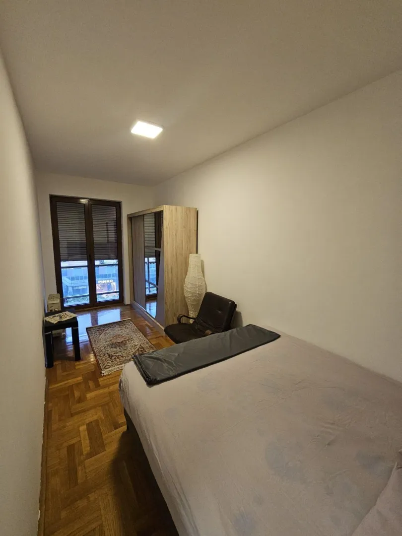 Svijetla spavaća soba sa francuskim krevetom i ormarom.