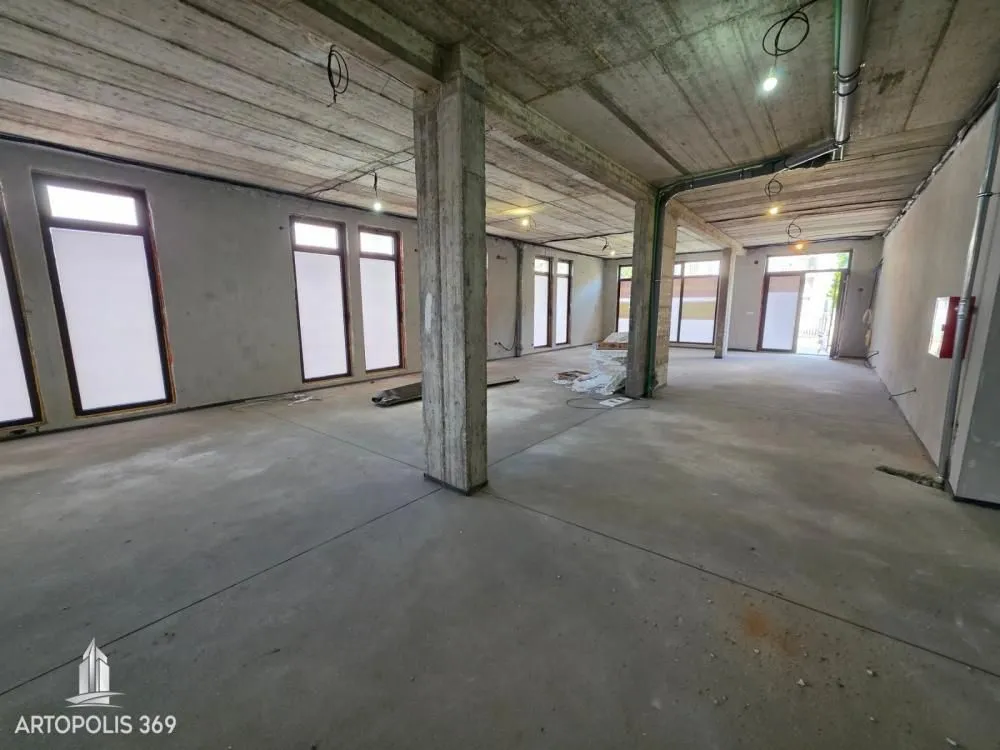 Large unfinished space under construction with pillars and windows.