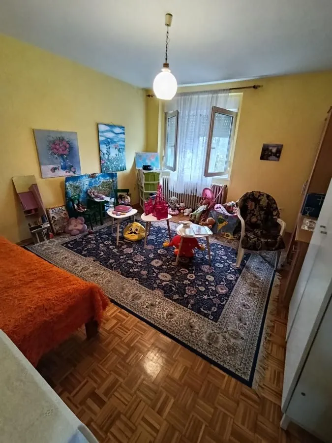 Dečja soba sa krevetom, velikim tepihom i igračkama.