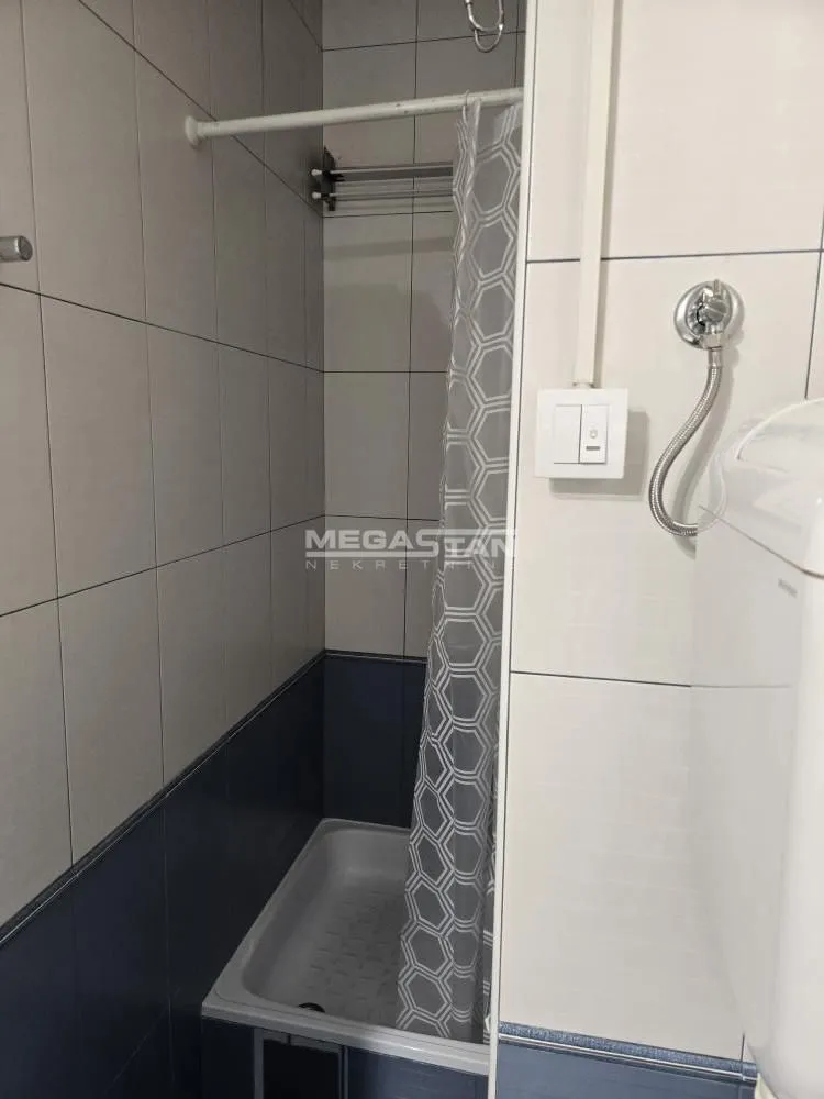 Small bathroom with a shower cabin and tiles.
