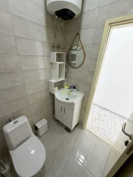 Small bathroom with a washbasin, mirror, and toilet. - image 3