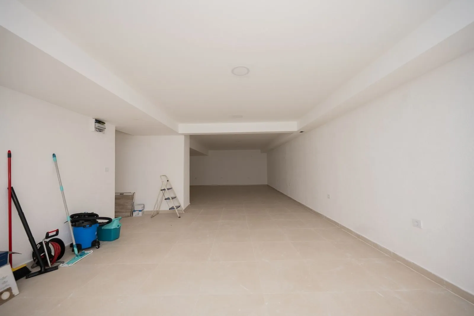 A spacious and bright empty room with light floor tiles.