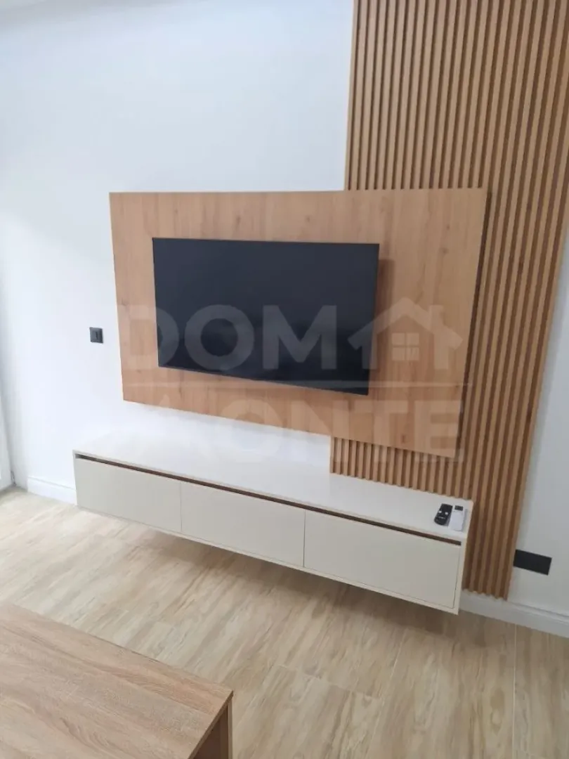 Living room with a TV and modern wooden wall panels.