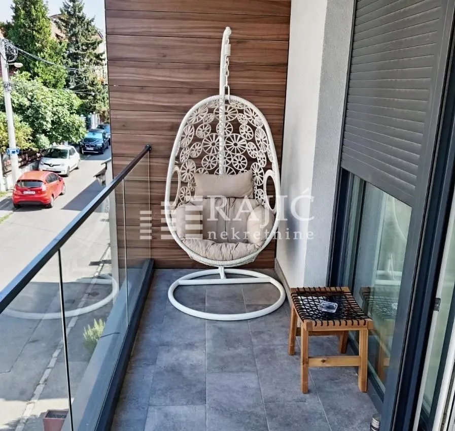 Modern furnished balcony with a hanging chair.