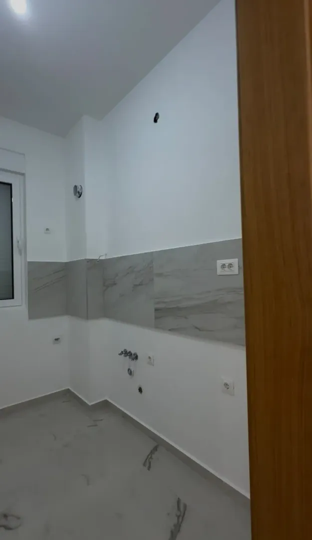 Nekoršćena kuhinja u bijeloj boji sa mermernim pločicama.