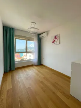Svijetla spavaća soba sa drvenim podom, klima uređajem i pogledom na more kroz prozor. - image 5