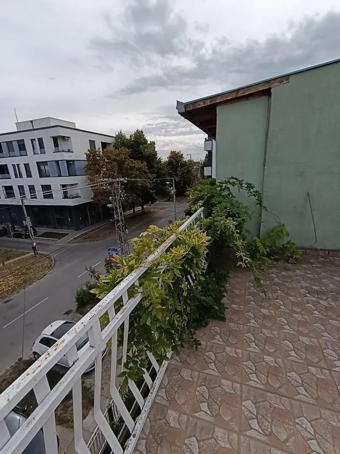 Terasa sa popločanim podom, metalnom ogradom i pogledom na ulicu i okolne zgrade.