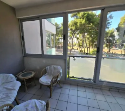 Enclosed balcony with seating furniture and a green view. - image 7