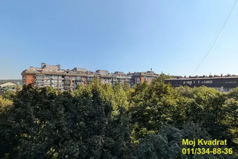 Pogled sa prozora na okolne zgrade i zelene krošnje drveća. - image 15