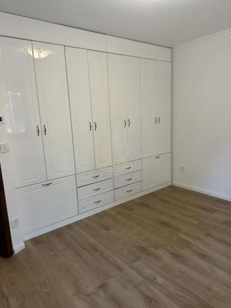 Bedroom with a large white built-in wardrobe and wooden flooring.