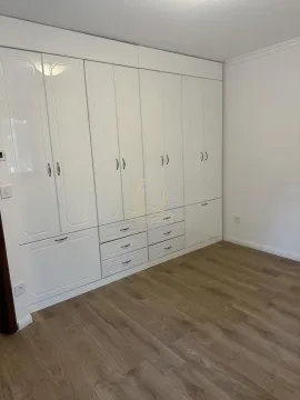 Bedroom with a large white built-in wardrobe and wooden flooring. - image 4