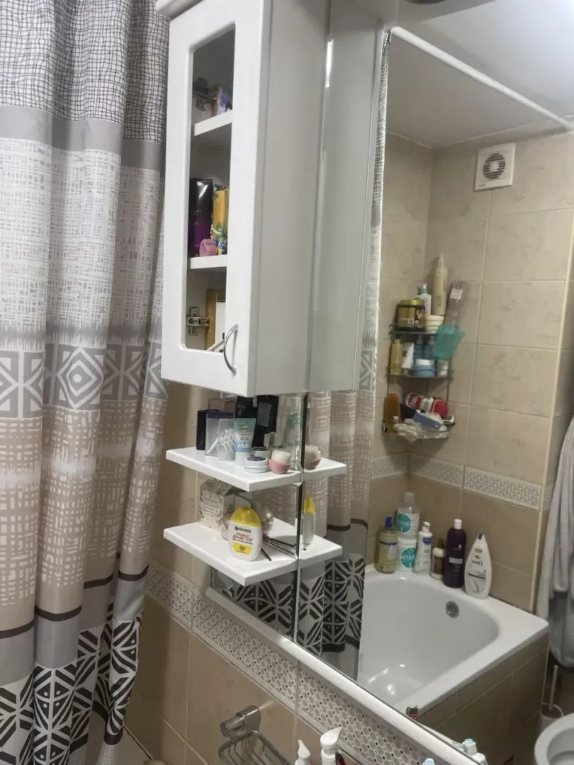 Small bathroom with a bathtub, mirrored cabinet, and shower curtain.