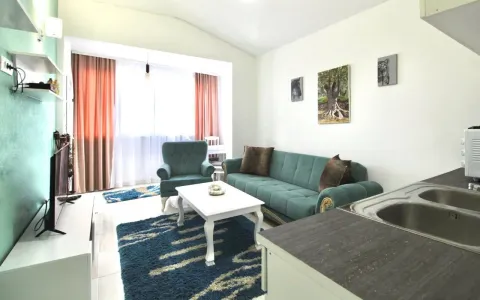 Living room with a sofa, coffee table, and a kitchen area in the corner. - image 2