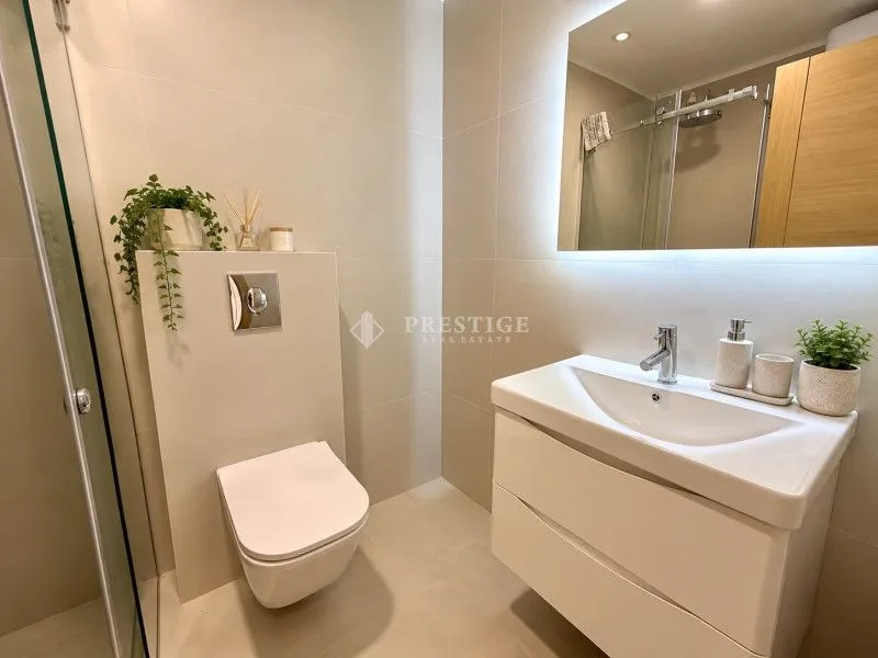 Moderno opremljeno kupatilo sa tuš kabinom, umivaonikom i ugradnom wc šoljom.