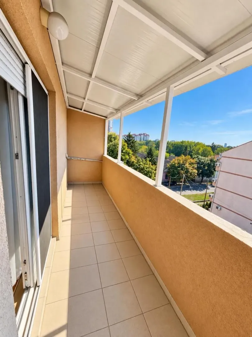 Natkriveni balkon sa popločanim podom i pogledom na okolinu.