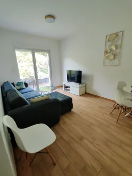 Living room with a sofa, TV, and dining table. - image 11