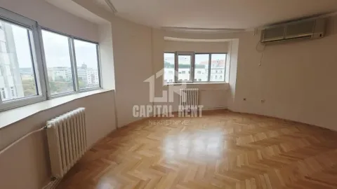 Empty living room with parquet flooring, radiators, and large windows. - image 3