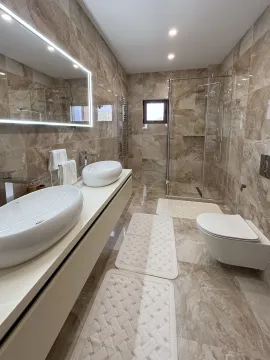 Modern bathroom with double sinks, walk-in shower, and wall-hung toilet. - image 5