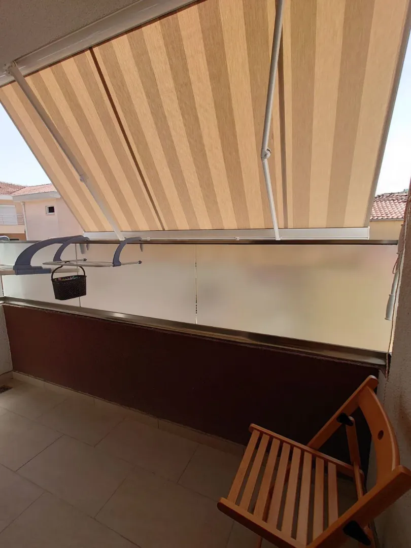 Covered balcony with an awning and a wooden chair.