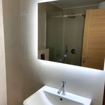 Modernly equipped bathroom with a washbasin and a backlit mirror. - image 7