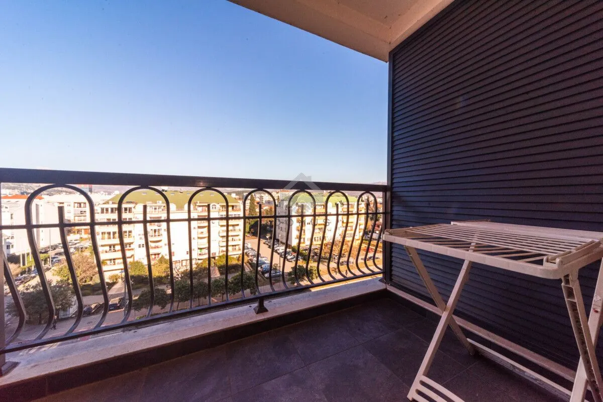 Natkriveni balkon sa metalnom ogradom i pogledom na grad.